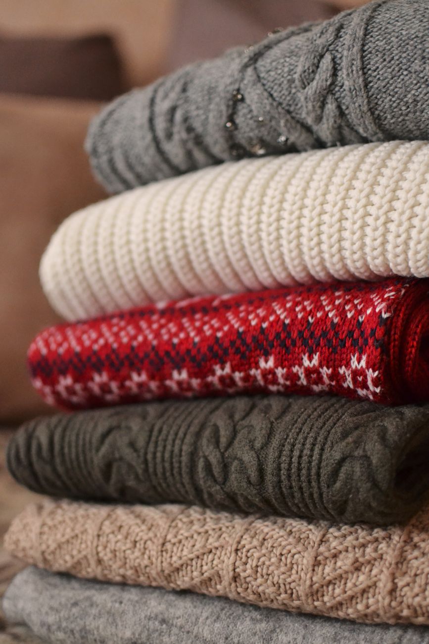 Pila de sweaters doblados de varios colores y texturas
