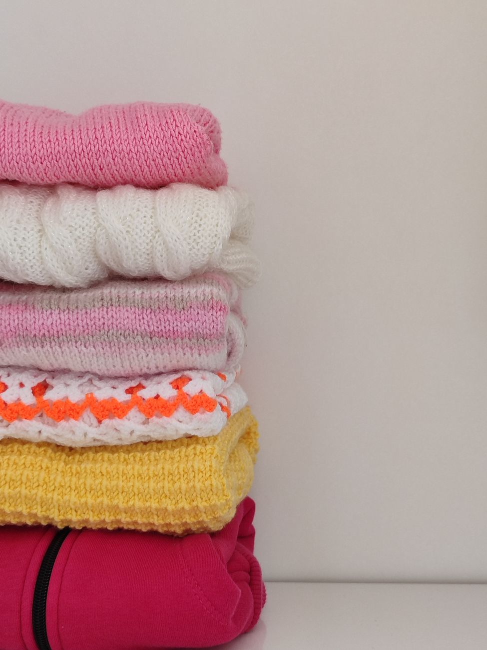 Conjunto de sweaters tejidos de colores apilados en un estante